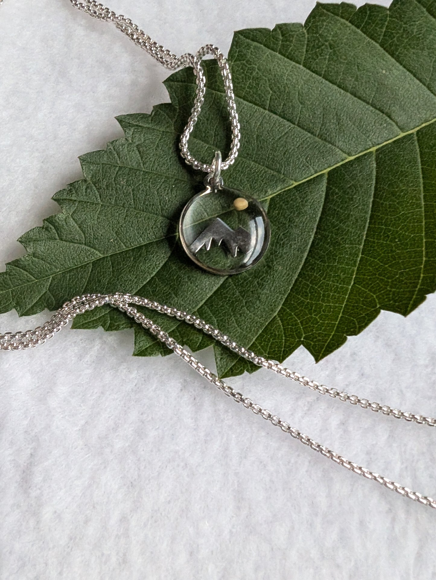Silver mountain mustard seed pendant on a long silver box chain